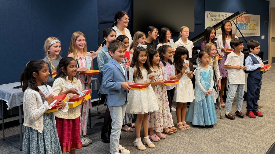 Students of the studio lined up with their awards and certificates beside a grand piano, with Mehrin Tavakoli behind them, at the 2026 recital